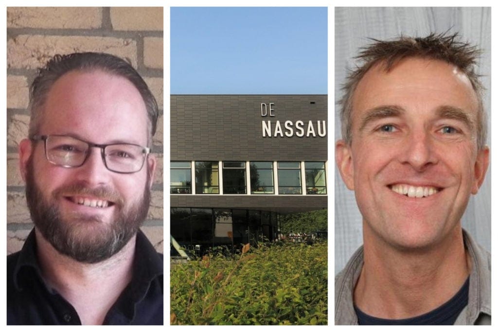 Two smiling men flank a building with "DE NASSAU" on its facade and green foliage.